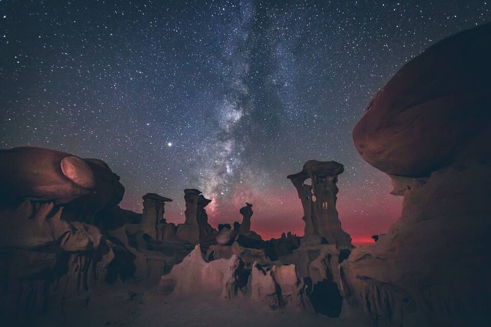 Un cielo notturno stellato con la Via Lattea sopra formazioni rocciose.