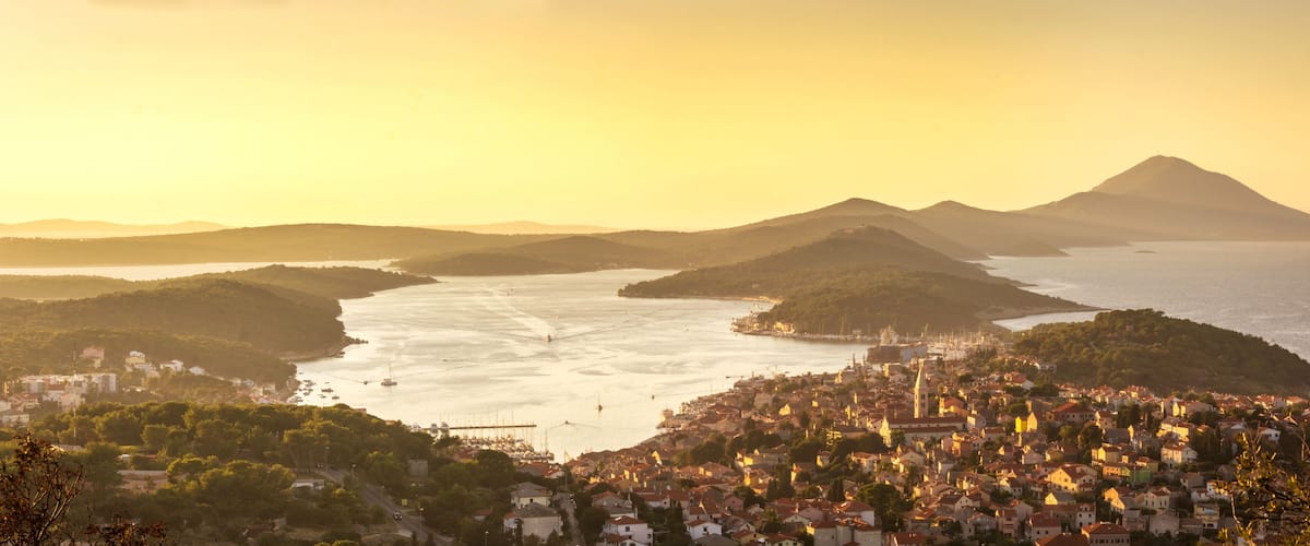 A coastal cityscape with a bay, a bridge, and a mountain in the background.