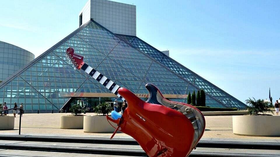 A large red sculpture of a guitar in front of a modern glass building.