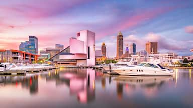 Marina com iates, um horizonte urbano moderno e um céu rosa e roxo.