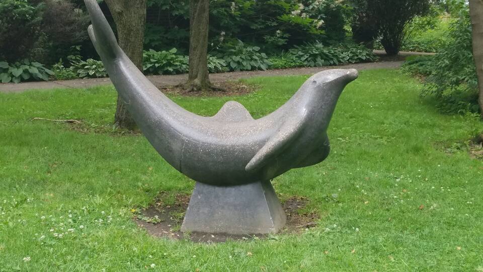 A stone sculpture of a bird in a park.