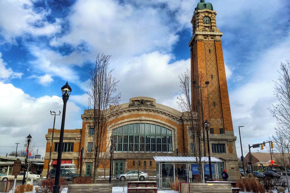 A historic building with a clock tower, benches, and a covered waiting area.