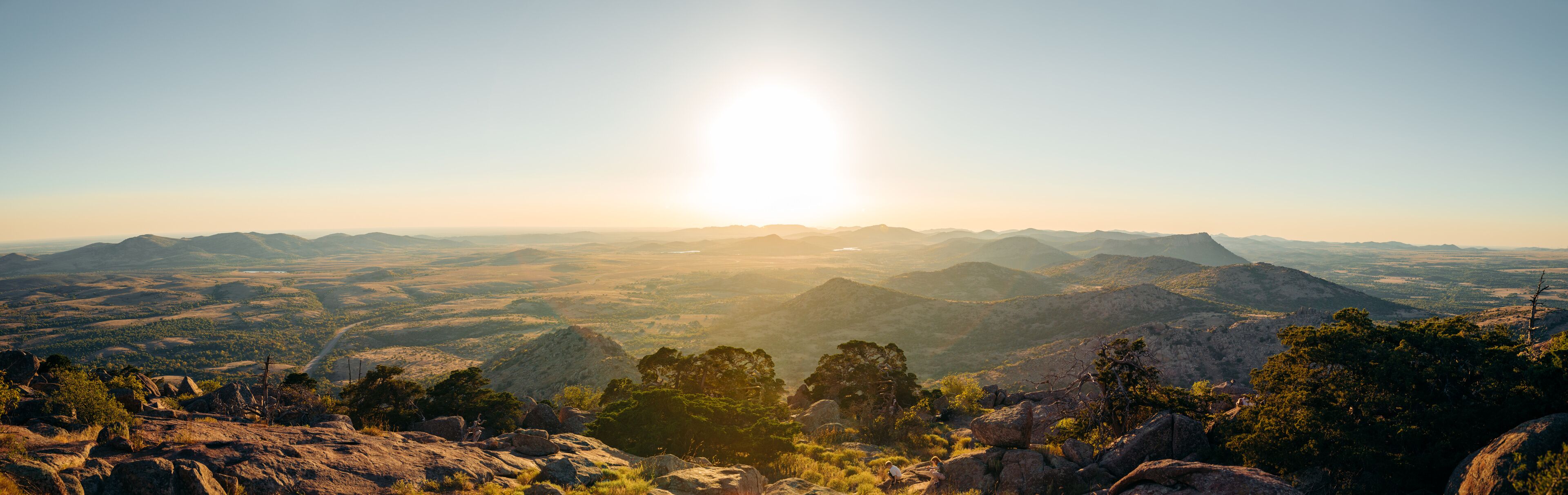 A mountainous landscape with a clear sky and the sun shining.