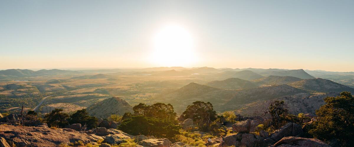 A mountainous landscape with a clear sky and the sun shining.
