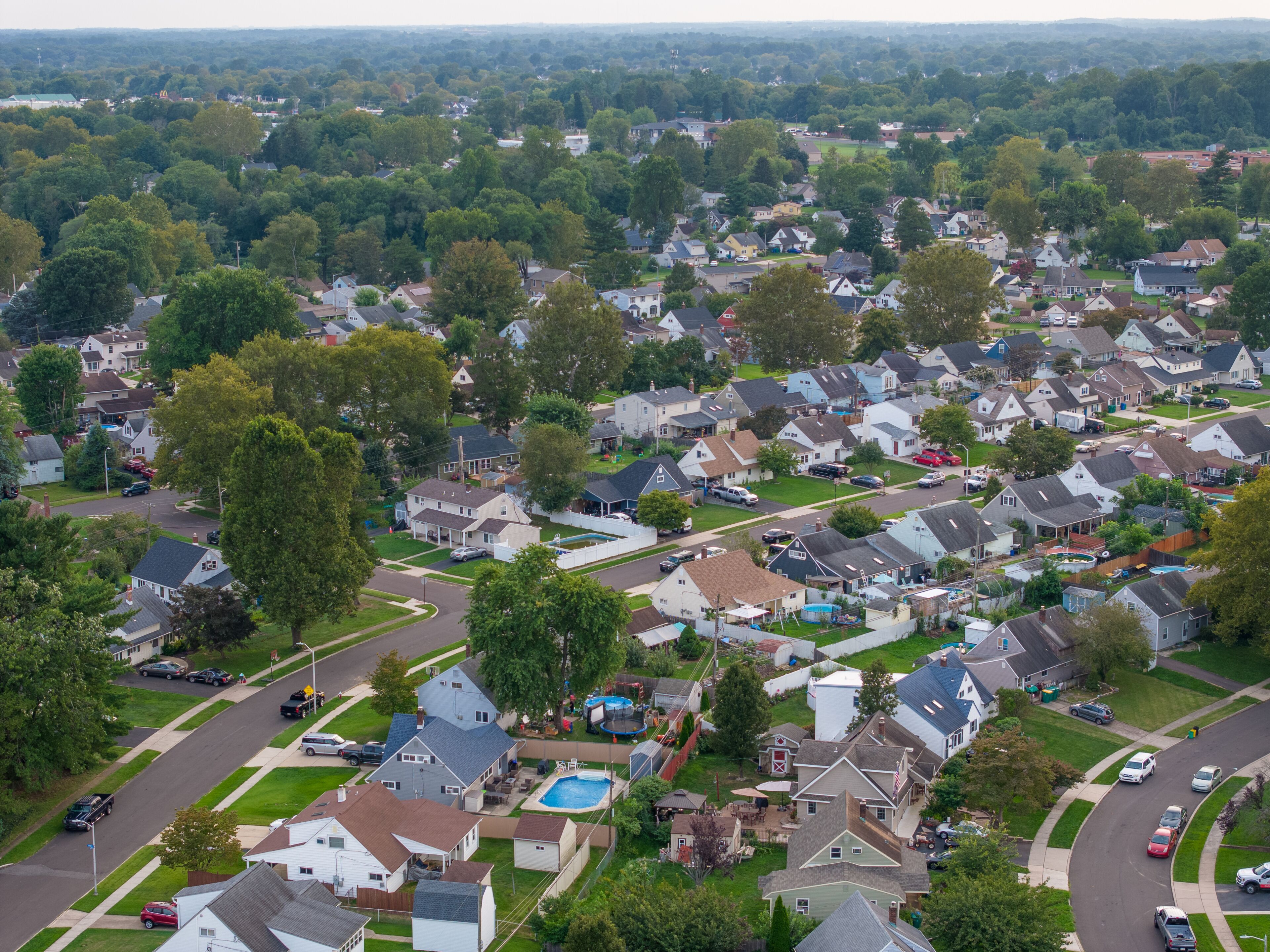 A suburban neighborhood with houses, streets, and a swimming pool.