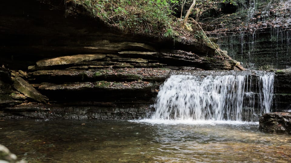 A waterfall cascading over a rocky cliff into a clear pool of water.