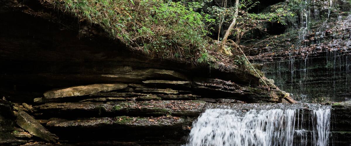 A waterfall cascading over a rocky cliff into a clear pool of water.