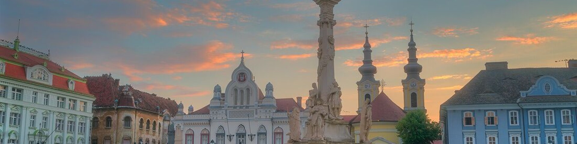 Una plaza histórica con un monumento central, rodeada de edificios coloridos y un cielo despejado.