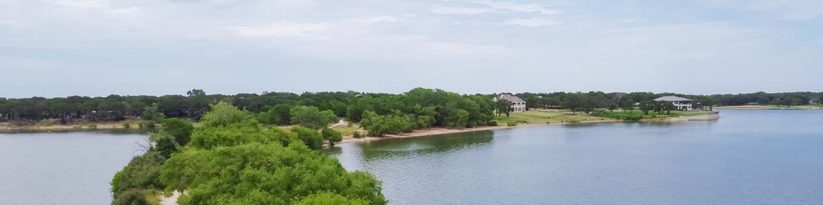 Top view lush green hiking trail lead to the lakeside neighborhood with upscale two story house in Lakewood Village, Texas, America