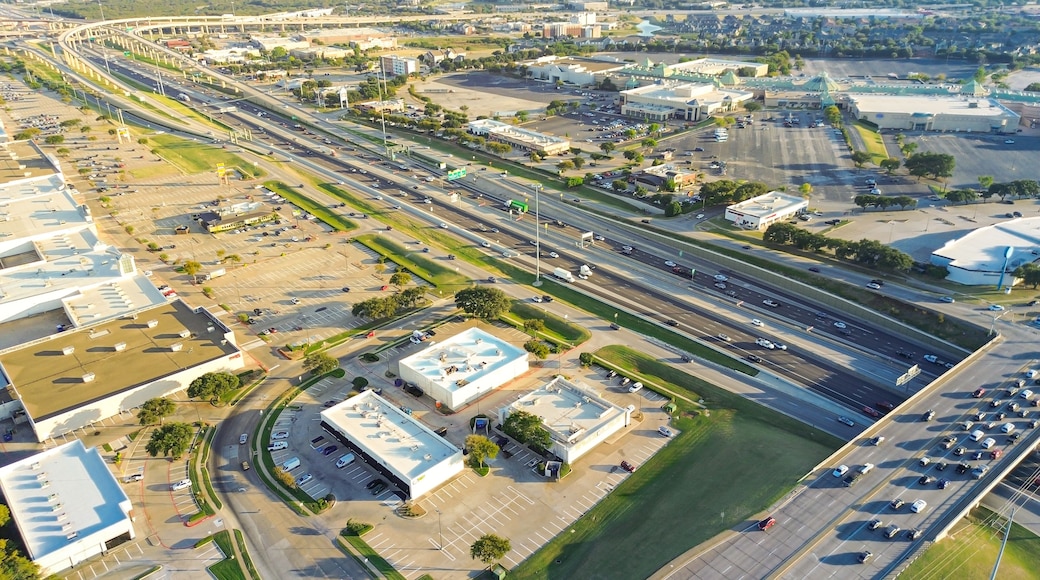 Stacked interchange viaduct highway in Lewisville, Texas featuring exit ramps, frontage roads, dense commercial development with strip malls, service centers, flat-roof buildings on both sides