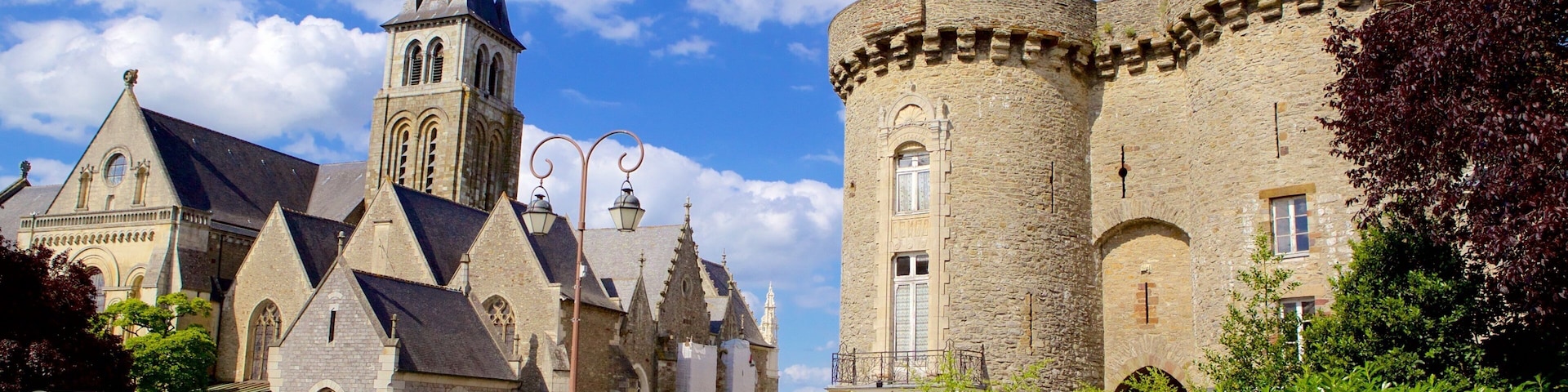 A historic church with a tall bell tower and a large stone building with a round tower.
