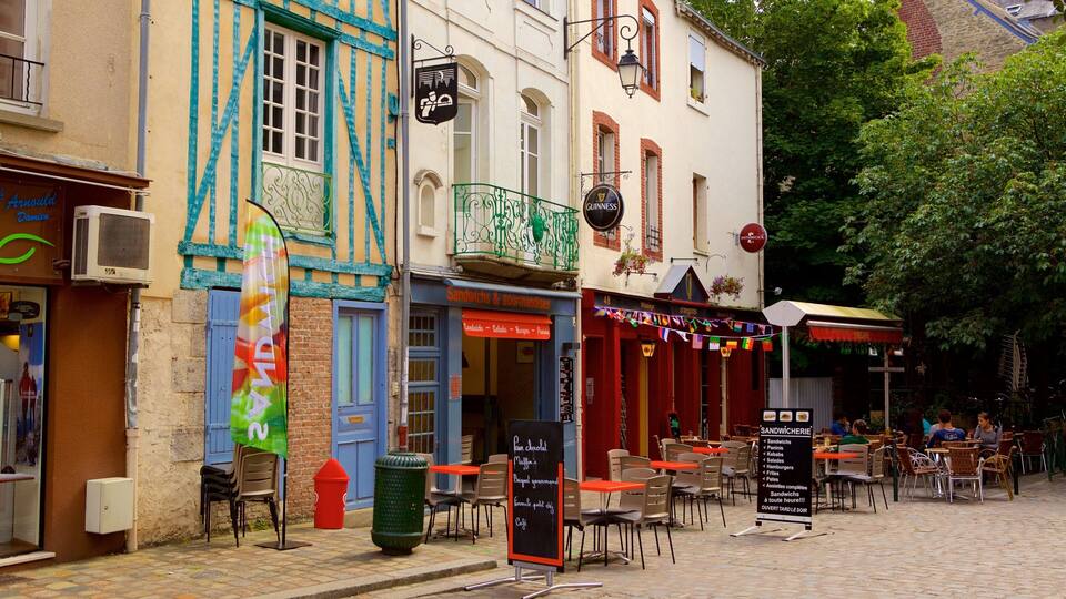A cobblestone street with outdoor seating at cafes, a sign for 'Sandwiches & gourmandises', and a 'Guinness' sign above a pub.