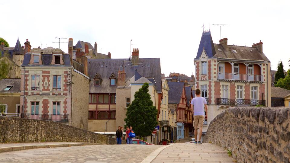 A cobblestone street with historic European buildings, a stone wall, and pedestrians.