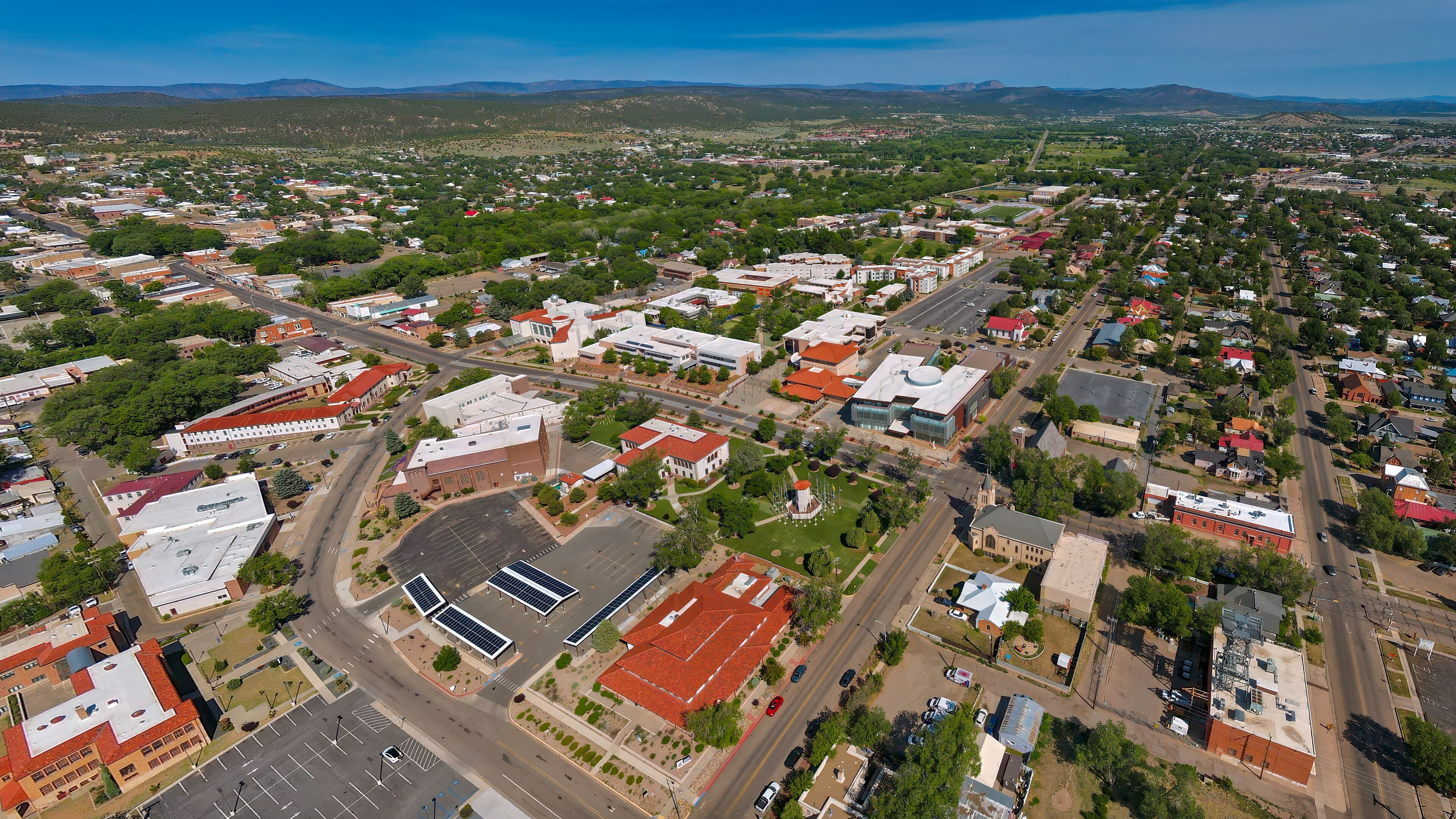 An aerial view of a town with a mix of residential and commercial buildings, roads, and green spaces.