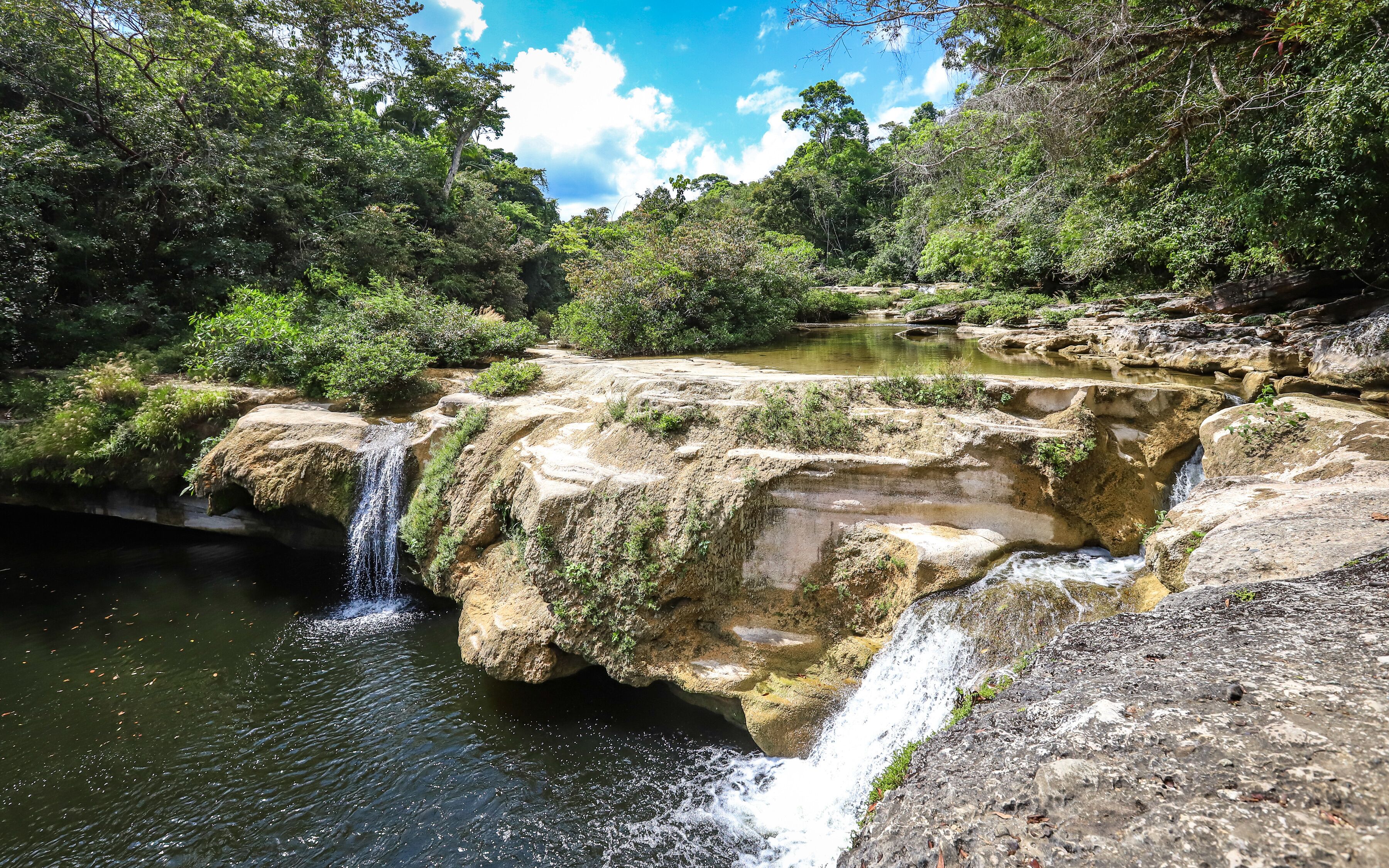 A waterfall cascading over rocky terrain surrounded by lush greenery.
