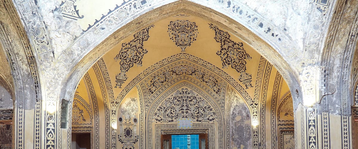 An ornate hall with intricate tile work and a central fountain.
