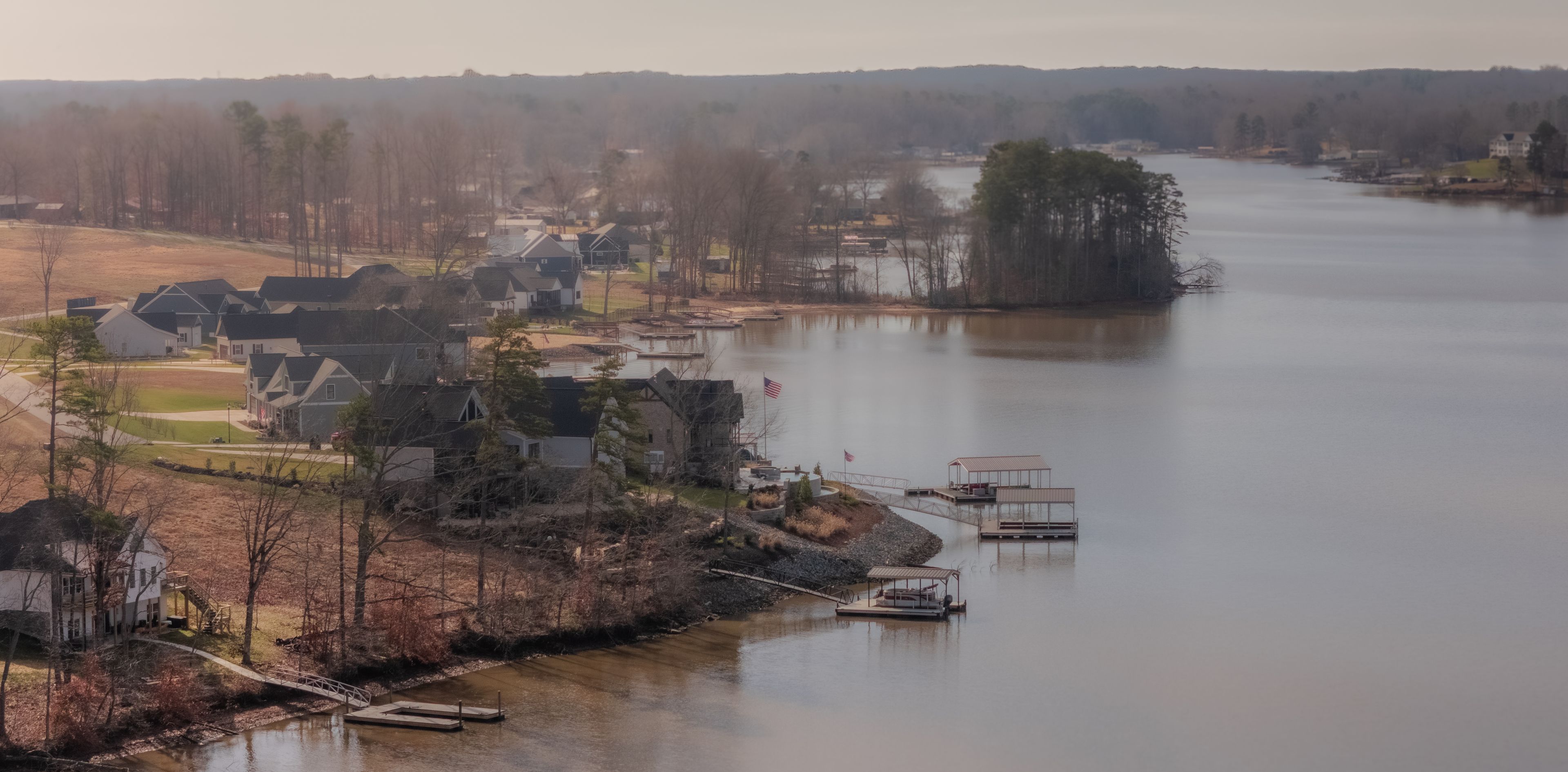 A lakeside community with houses, docks, and a bridge.