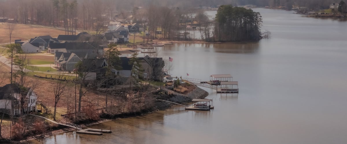 A lakeside community with houses, docks, and a bridge.