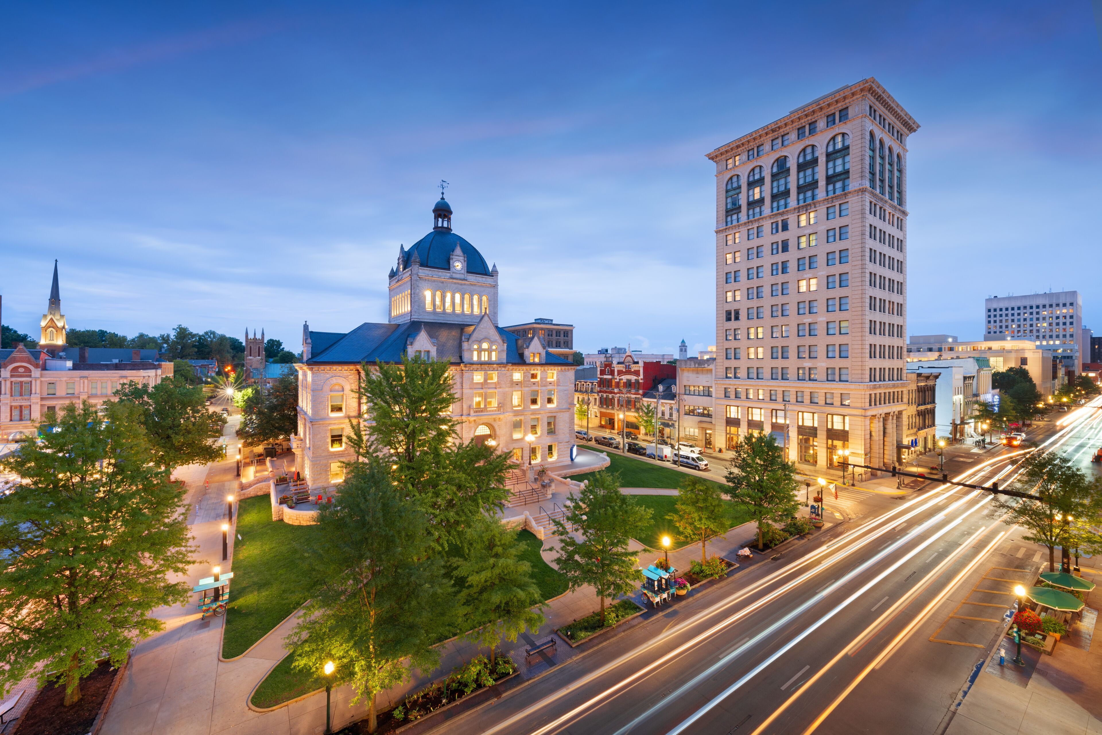 A cityscape with a prominent building with a dome, a tall skyscraper, and a busy intersection with light trails.