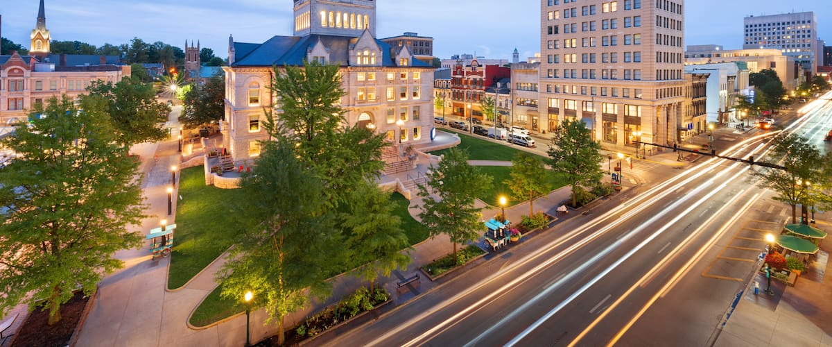 A cityscape with a prominent building with a dome, a tall skyscraper, and a busy intersection with light trails.