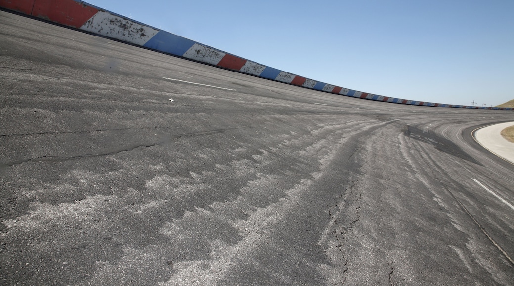 A curved racetrack with a concrete surface and a colorful barrier.