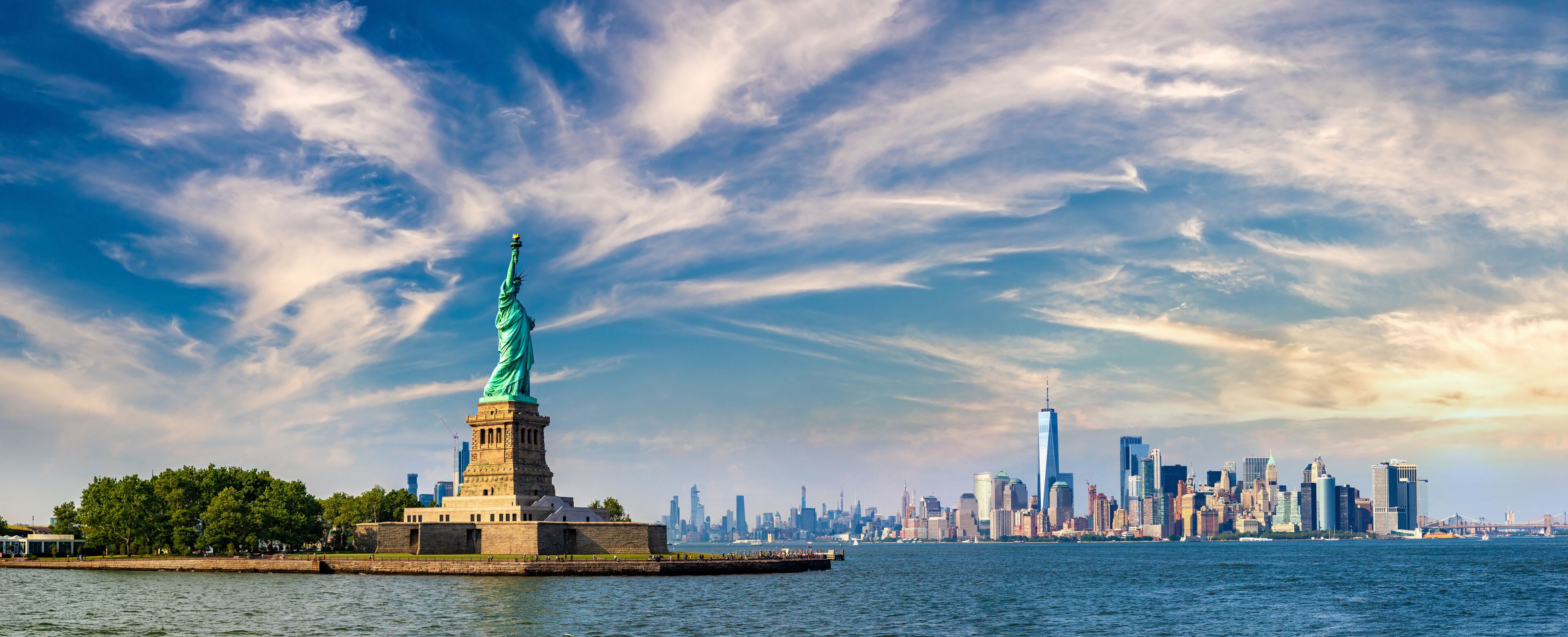 The Statue of Liberty on Liberty Island with the New York City skyline in the background.