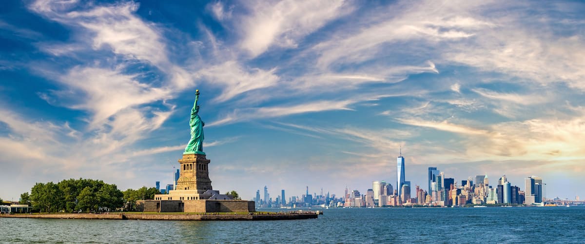 The Statue of Liberty on Liberty Island with the New York City skyline in the background.