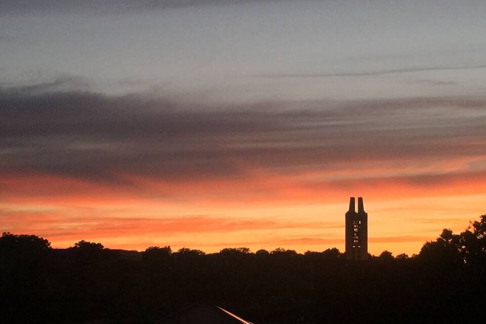 Auringonlasku, jossa tornin siluetti erottuu oranssin ja punaisen sävyissä hehkuvaa taivasta vasten.