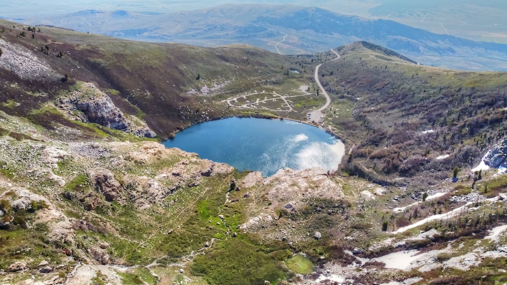 A mountainous landscape with a lake, winding roads, and sparse vegetation.
