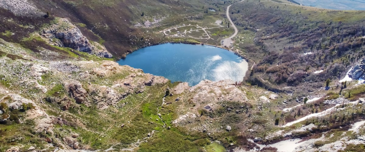 A mountainous landscape with a lake, winding roads, and sparse vegetation.