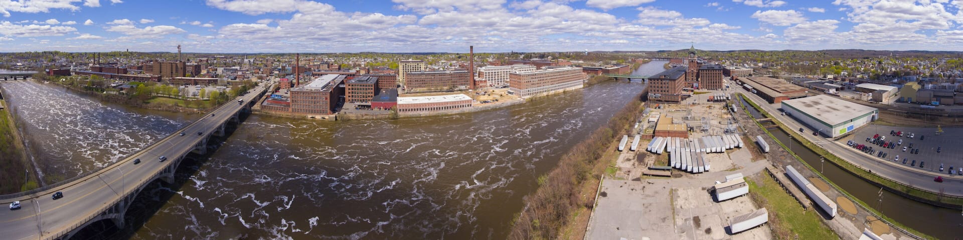 A river with industrial buildings and a bridge.