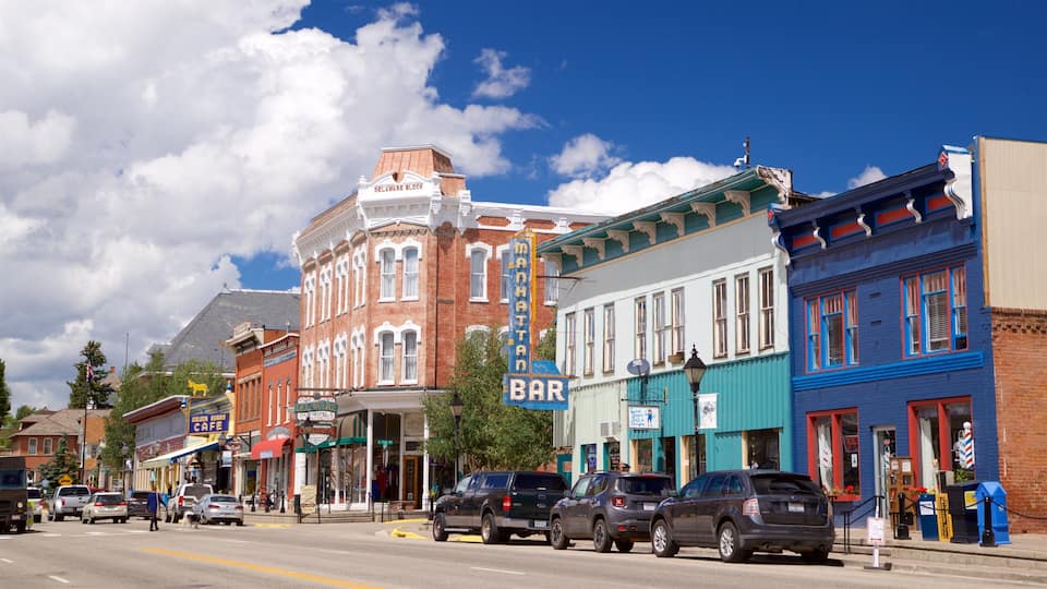 A street lined with historic buildings, including a prominent red brick building with a mansard roof and a blue building with red trim.