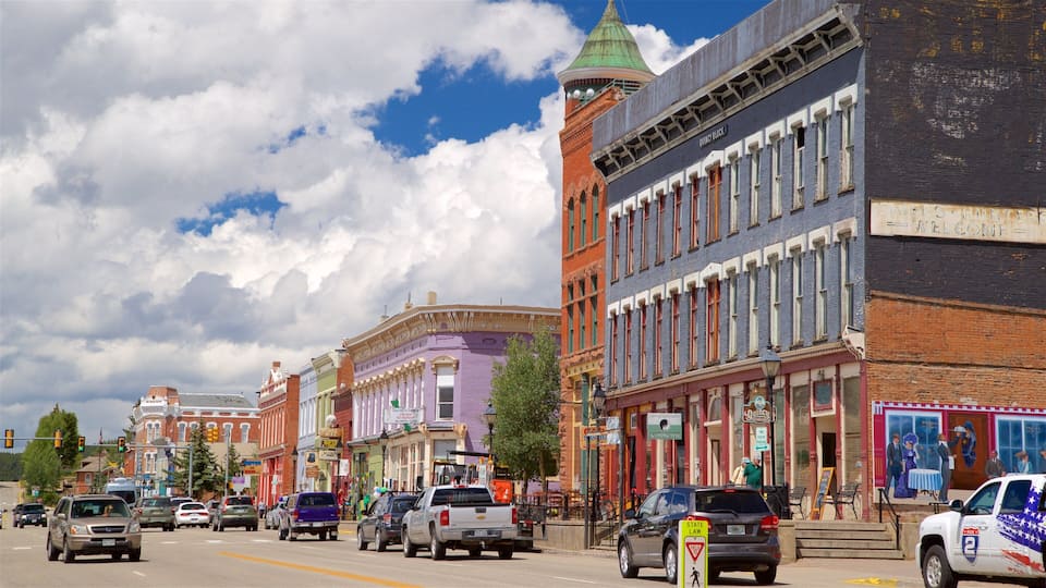 A street lined with colorful historic buildings, a mix of commercial and residential structures, and a clear blue sky with clouds.