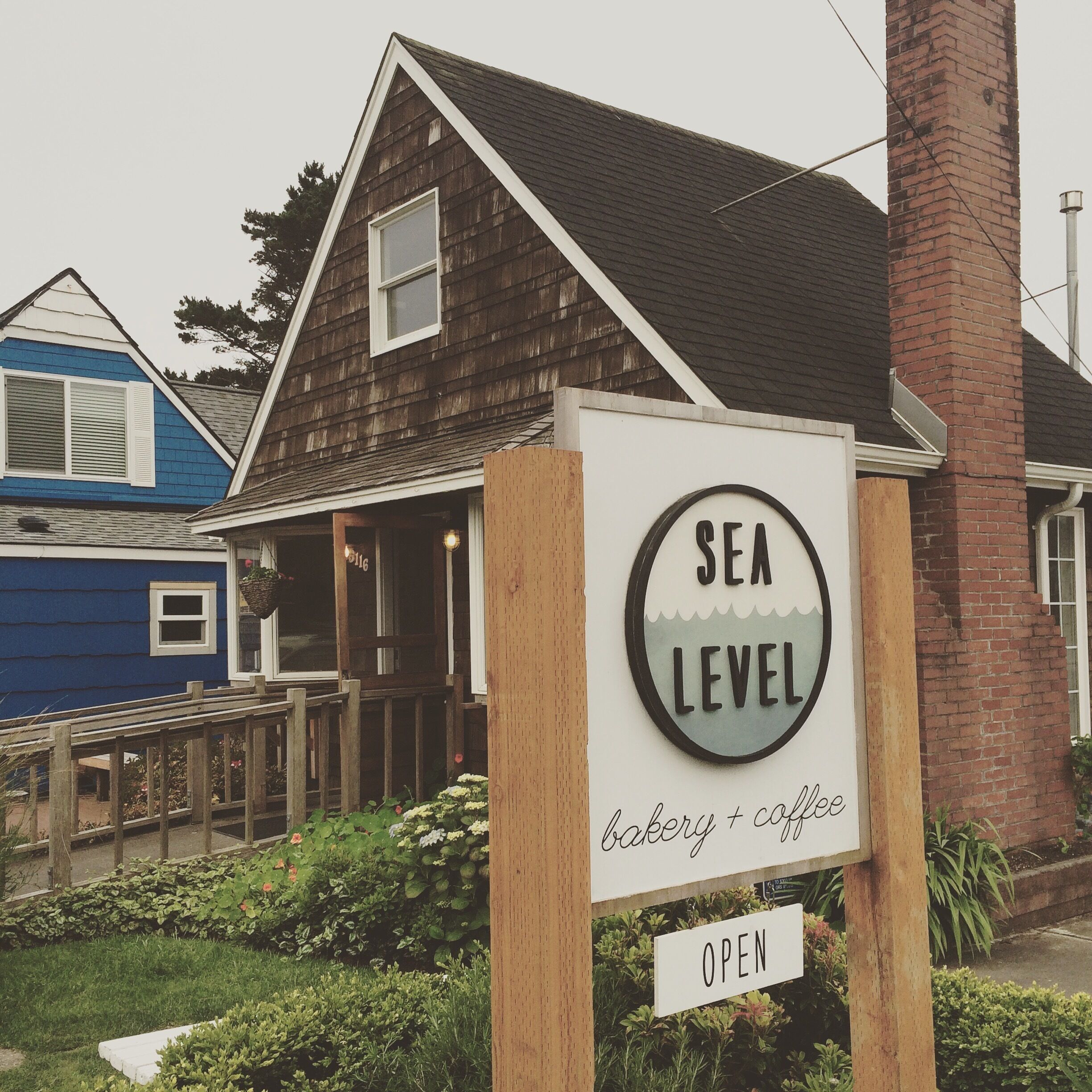 A wooden building with a sign that reads "SEA LEVEL bakery & coffee" and an "OPEN" sign below it.