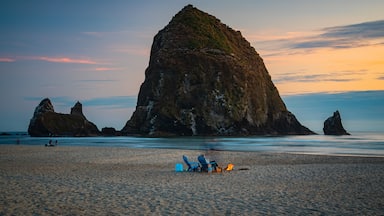 A beach with large rock formations and a sunset.
