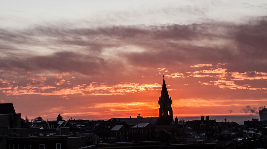 dramatic sunrise of the Baltimore skyline with a church steeple on the foreground.