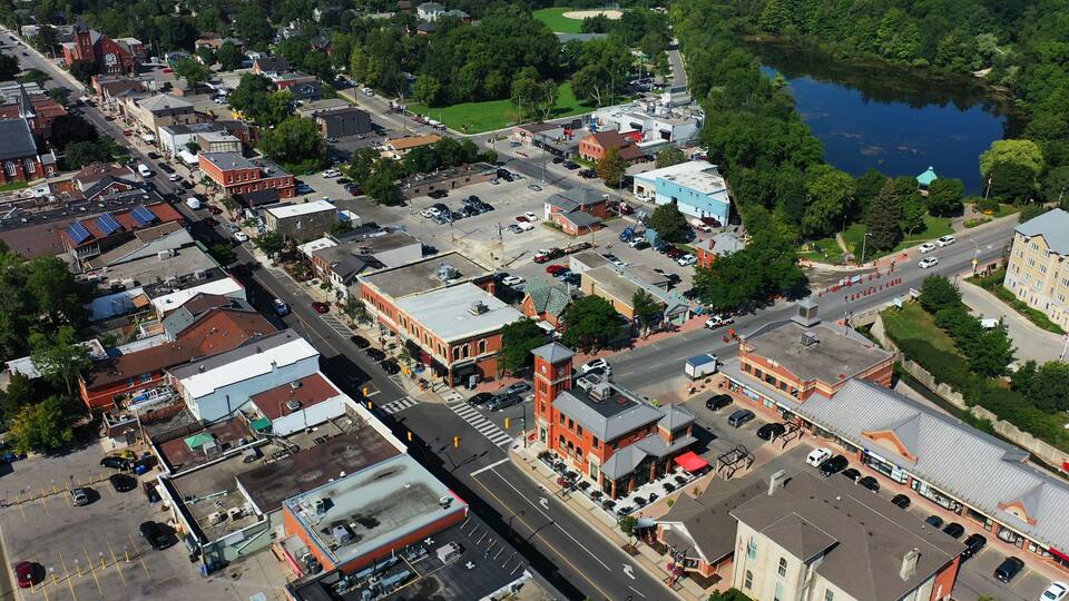 An aerial view of a town with a mix of historic and modern buildings, a main street, and a lake in the background.