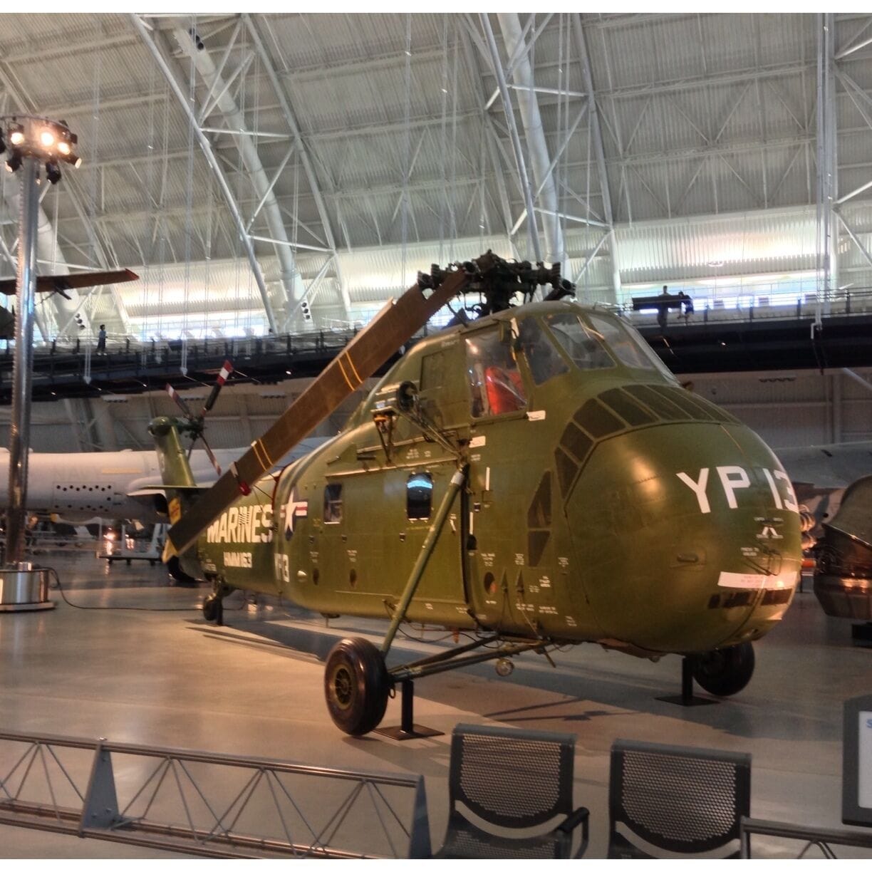 A military helicopter with the markings "YP 13" in a hangar.