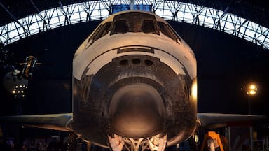 Un transbordador espacial en exhibición en un museo con un amplio techo de cristal.