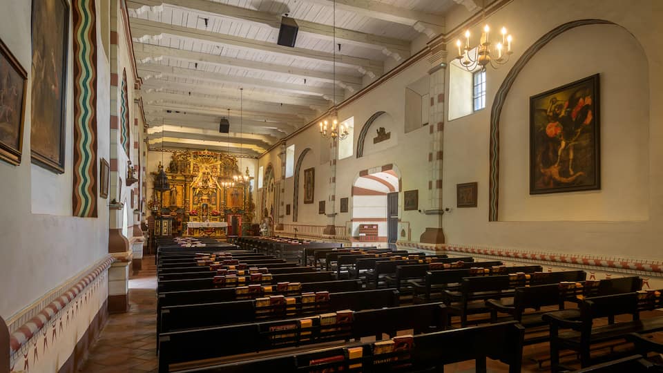 An interior of a church with pews, a chandelier, and religious artwork.