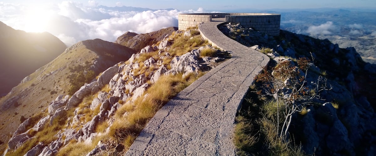A mountainous landscape with a stone pathway leading to a circular stone structure.