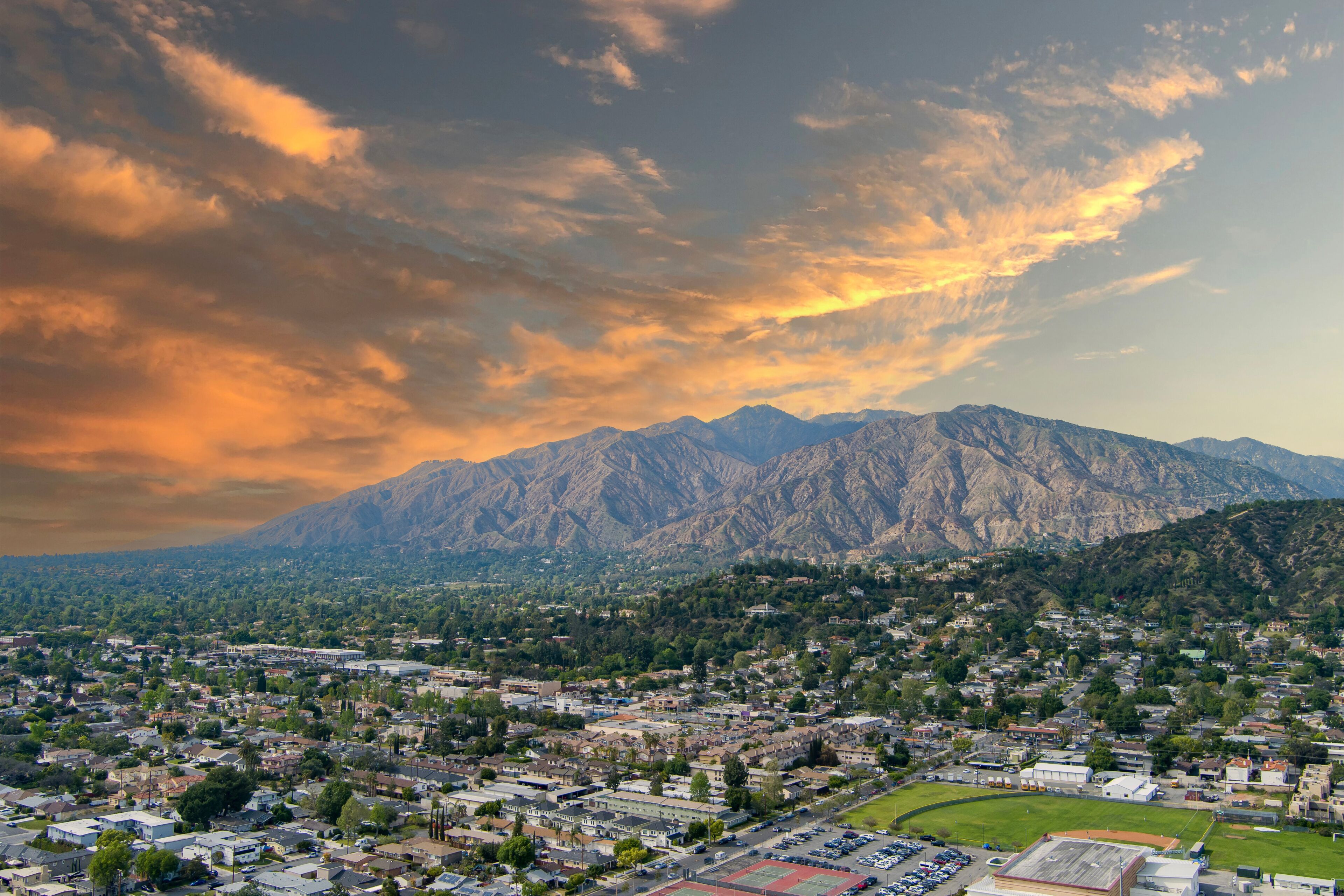 aerial shot of majestic mountain ranges with homes, lush green trees and cars on the street in Monrovia California USA