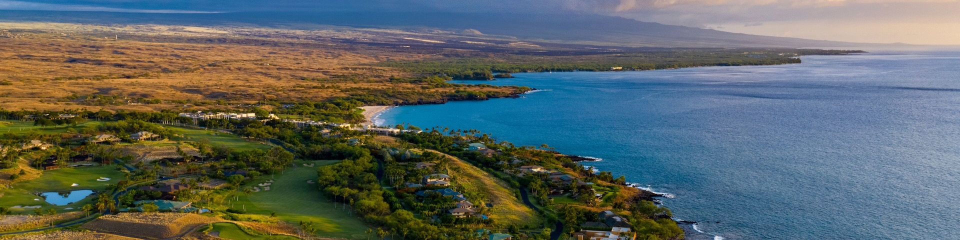 Un paysage côtier comprenant un terrain de golf, une plage et l’océan.