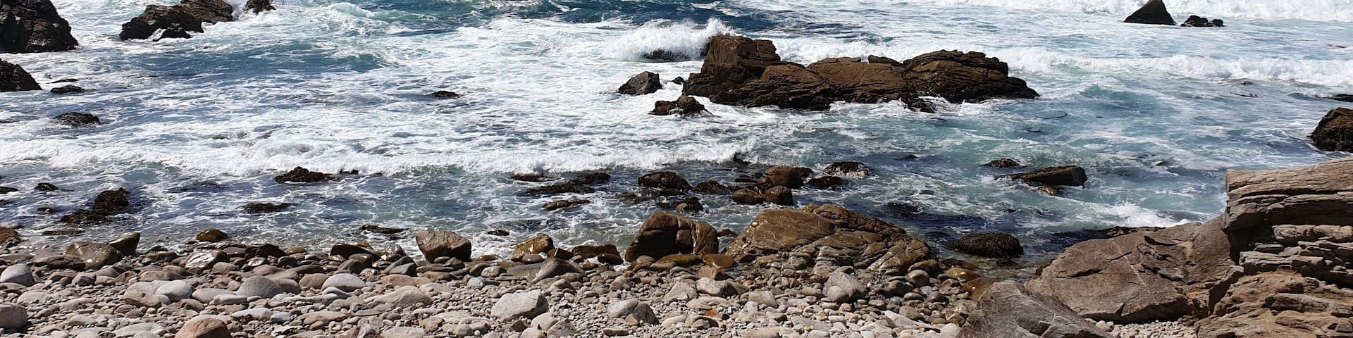 A rocky shoreline with turbulent ocean waves crashing against the rocks.