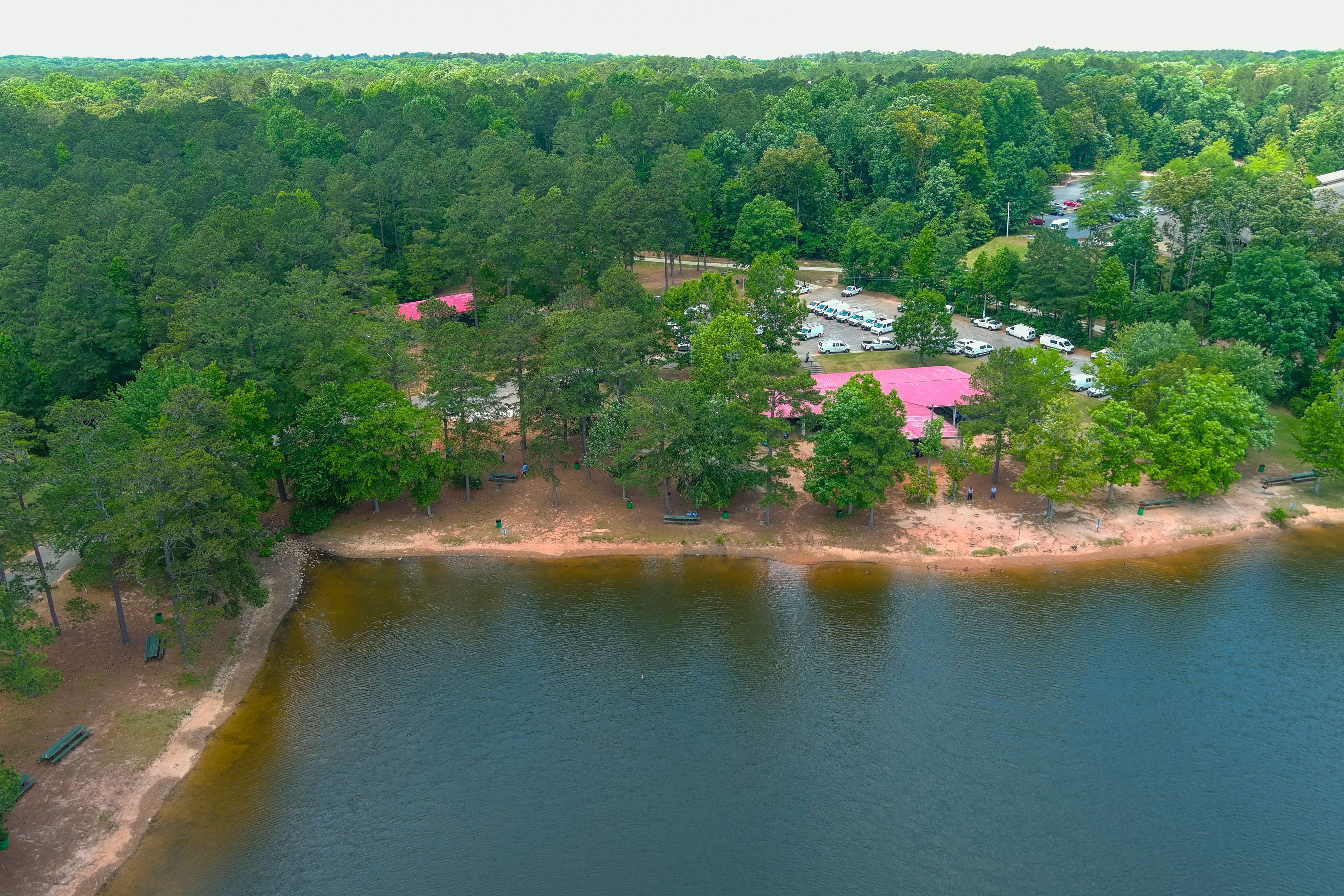 a gorgeous green rippling lake surrounded by lush green trees, grass and plants with blue sky and clouds and buildings among the trees at Lake Spivey Recreation Center in Jonesboro Georgia USA