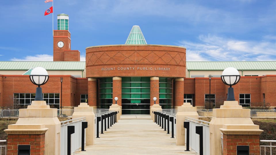 The Blount County Public Library with a brick facade, a clock tower, and a green roof.