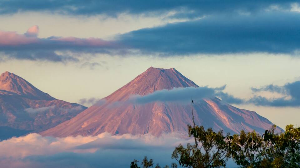 Two snow-capped mountains with clouds below.