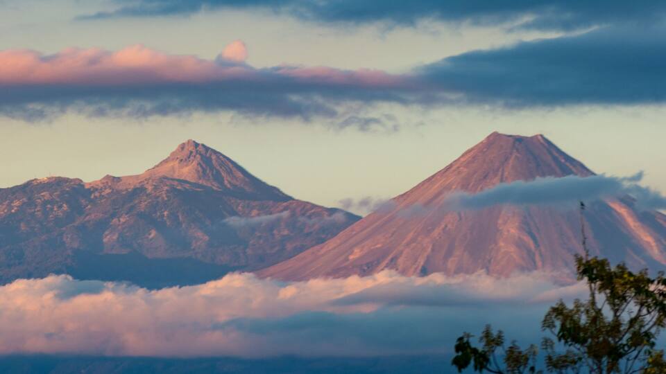 A mountain range with two prominent peaks, one partially covered by clouds.