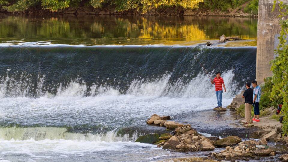 A waterfall with people standing on rocks at the base.