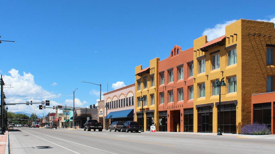 A street lined with colorful buildings, traffic lights, and a clear blue sky.